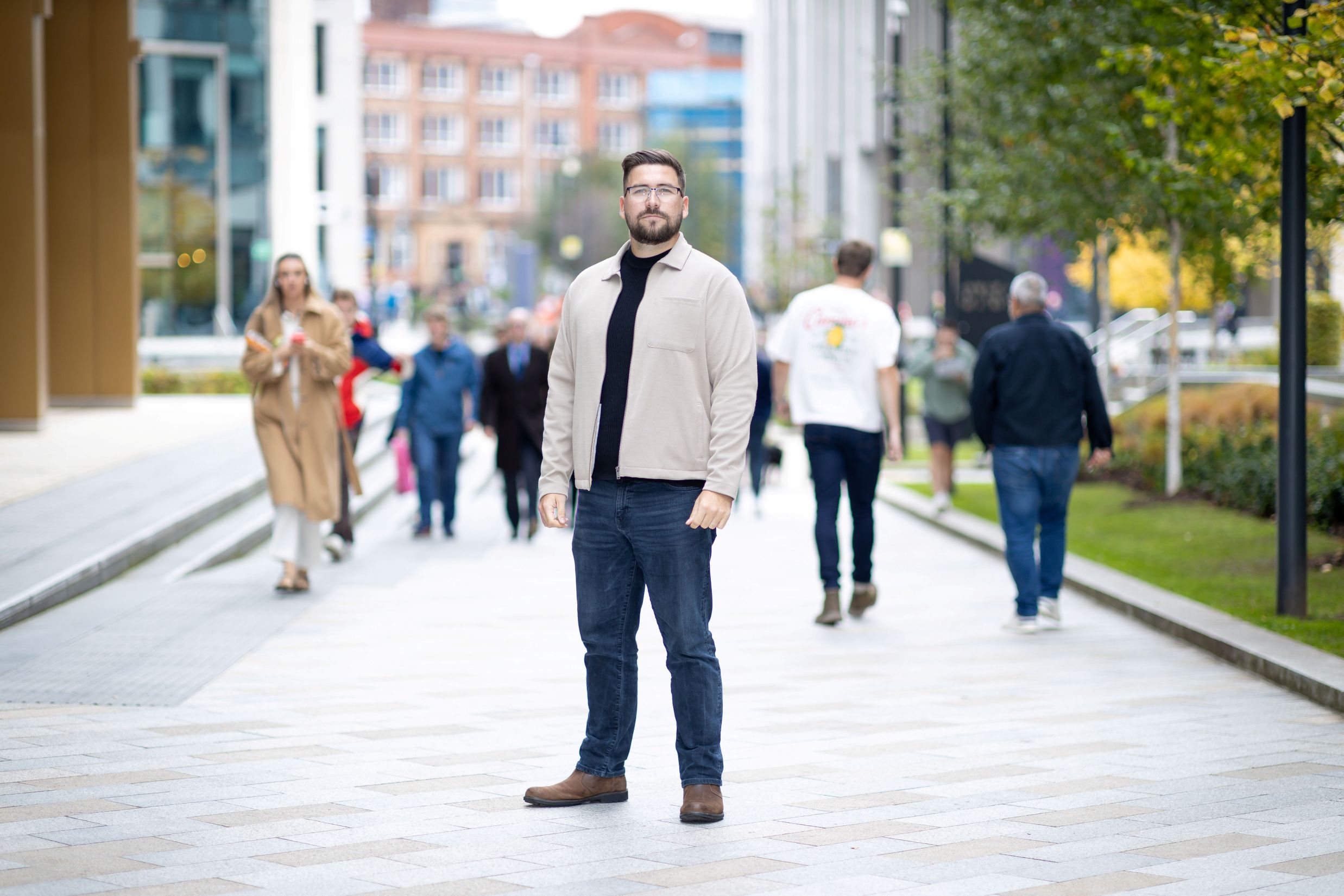 Dan Taylor standing outside NHS England offices with people walking in the street in the background.